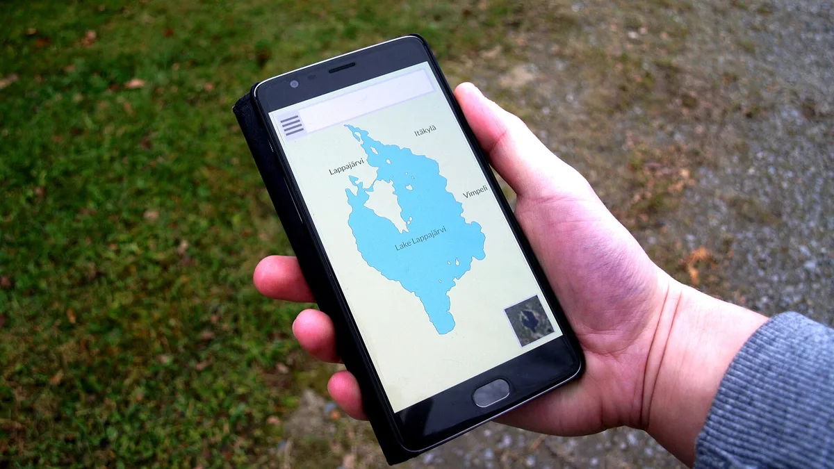 Une main tient un smartphone qui affiche une application de carte