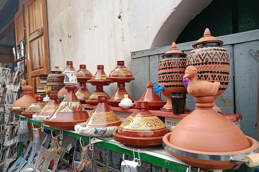 Des tajines et des poteries marocaines décorées exposés devant une boutique à Fès
