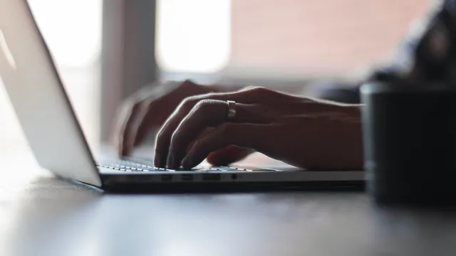 Des mains tapent sur le clavier d'un ordinateur portable dans une lumière douce