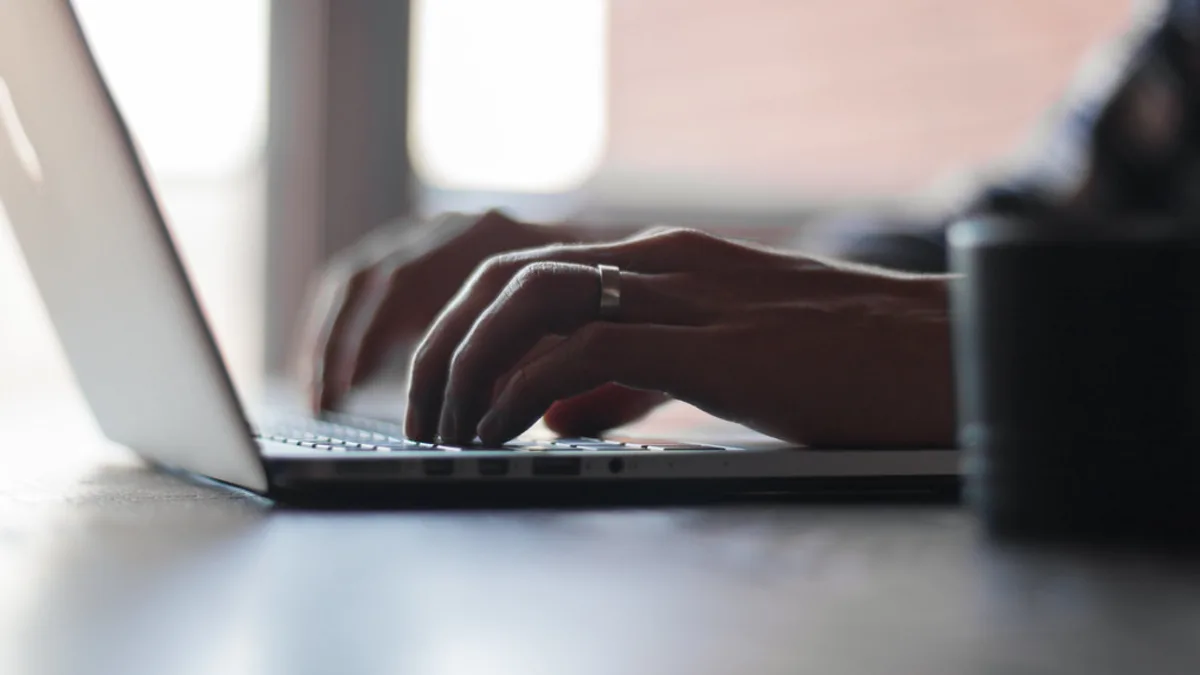 Des mains tapent sur le clavier d'un ordinateur portable dans une lumière douce