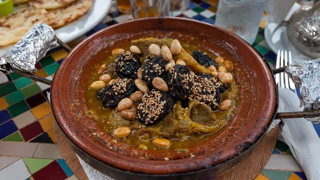 Un tajine à la viande garni de pruneaux et d'amandes, servi sur une table en zellige