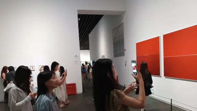 Visiteuses photographiant des œuvres avec leur smartphone dans une galerie d'art lumineuse